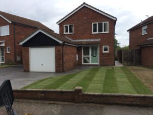 new front garden lawn laid infront of a house with garage